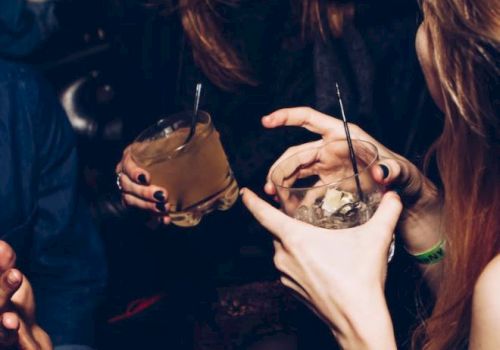 People are holding drinks and laughing together, suggesting a lively social gathering with a fun atmosphere.