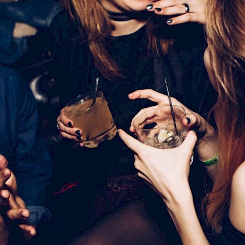 People are holding drinks and laughing together, suggesting a lively social gathering with a fun atmosphere.