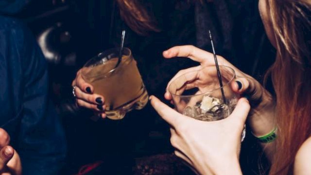 People are holding drinks and laughing together, suggesting a lively social gathering with a fun atmosphere.