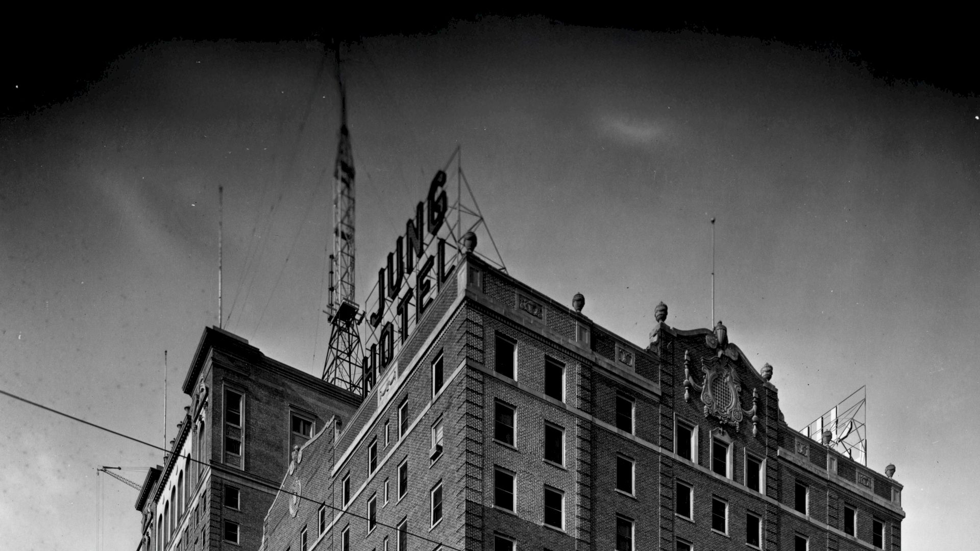 The image shows the upper portion of a building with a sign reading "JUNG HOTEL," with a tower structure visible on the roof.
