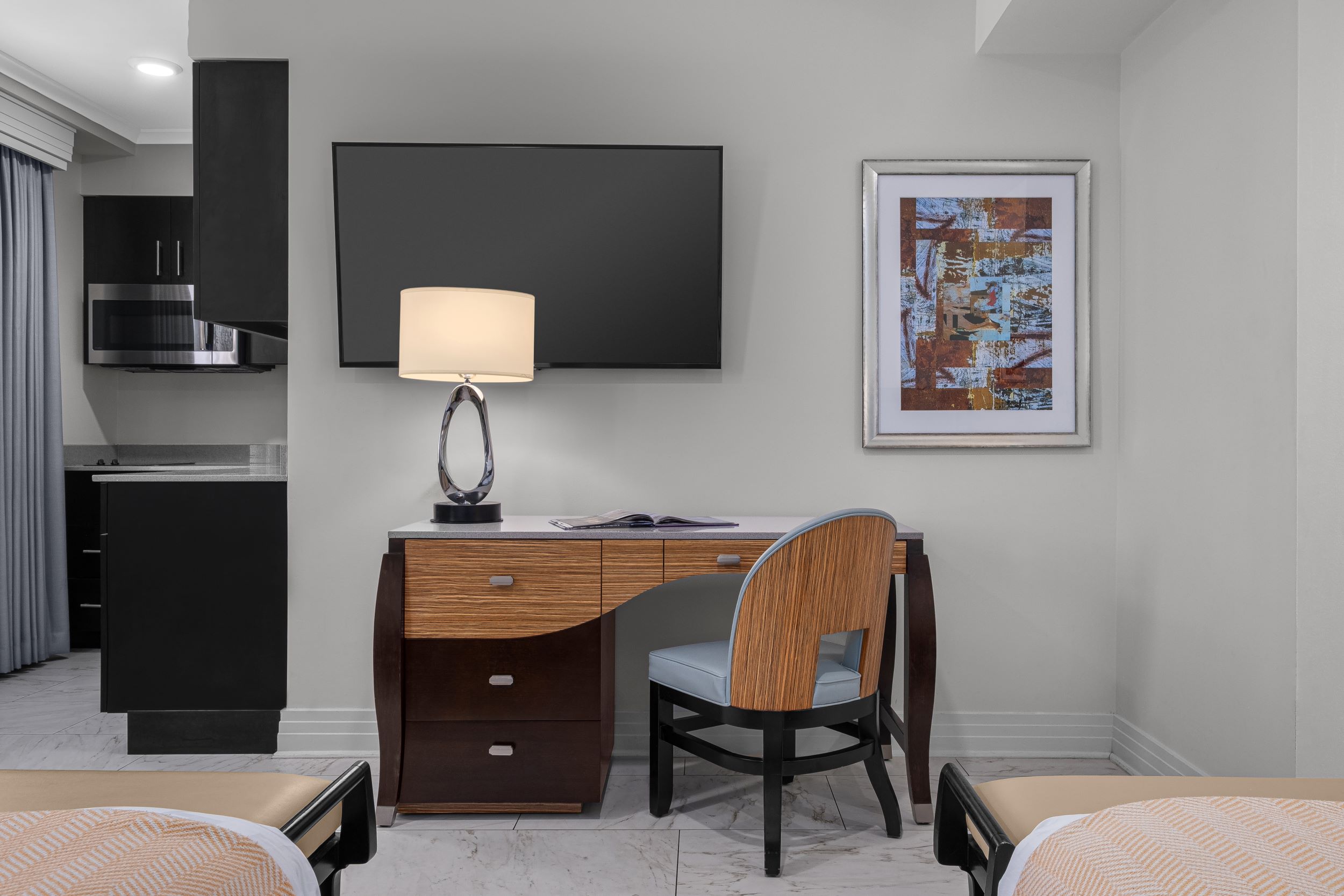 Hotel room desk with chair, lamp, and wall-mounted TV