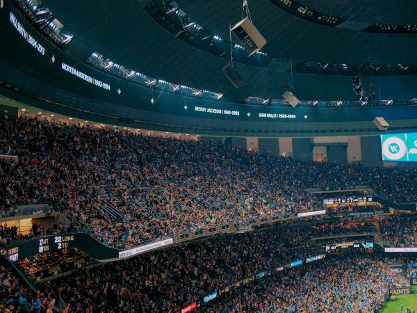 A packed stadium with a large crowd, displaying player names and years on the interior.