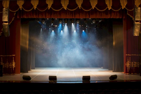 A theater stage with curtains, lights, and a misty atmosphere, ready for a performance.