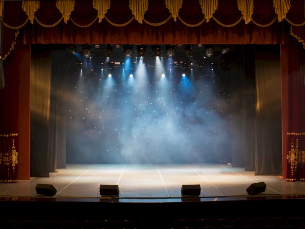 A theater stage with curtains, lights, and a misty atmosphere, ready for a performance.