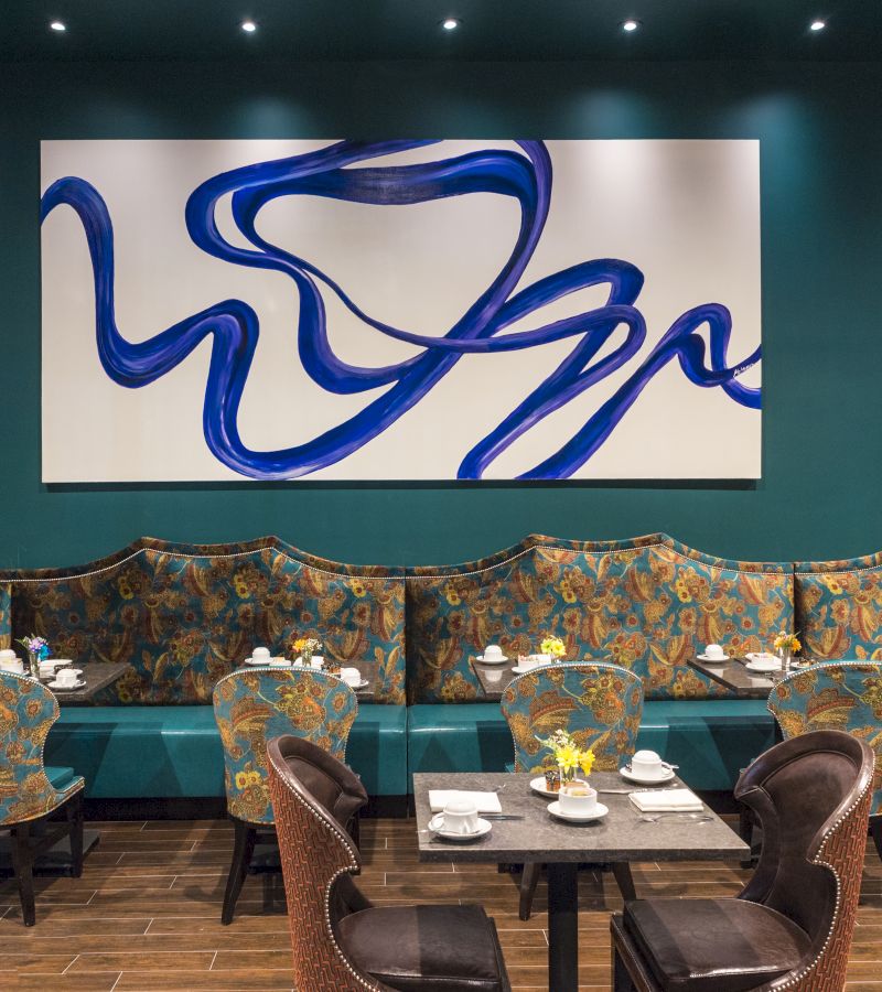 a dining area with tables and chairs and a large abstract art piece on the wall