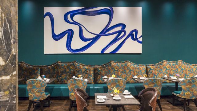 A dining area with booths and tables set for meals, featuring a large abstract art piece on the wall.