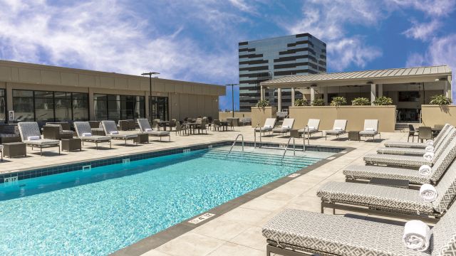 A swimming pool with lounge chairs and towels on a sunny day.