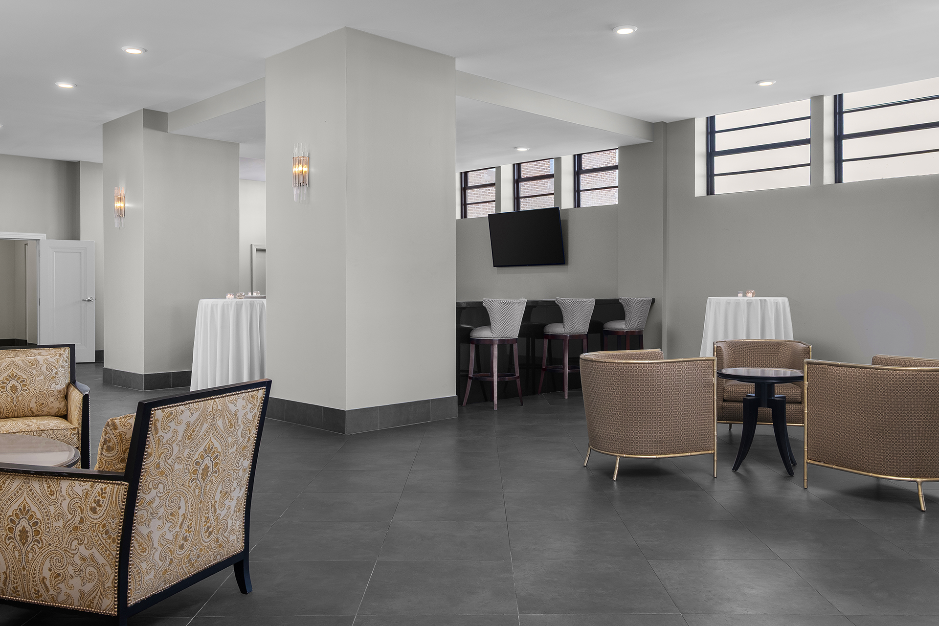 A modern lobby lounge with seating areas, a bar, and a TV on the wall.