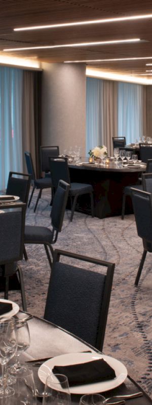 A banquet hall with round tables, chairs, and elegant table settings, ready for an event or gathering.